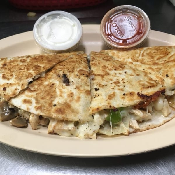 Chicken and mushroom quesadilla with melted cheese, served with sour cream and salsa.