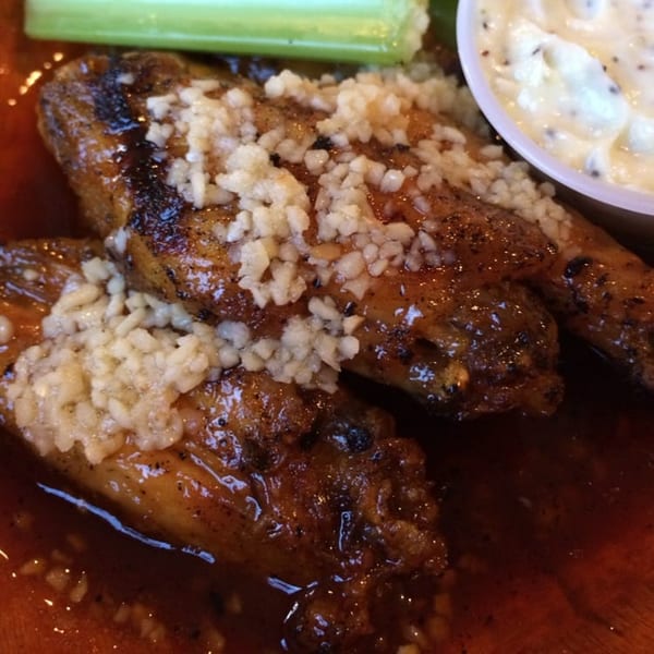 Close-up of garlic parmesan wings from Wings Plus of Lake Worth, with celery and ranch.